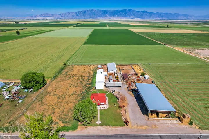 Expansive agricultural property featuring a red residential structure, multiple outbuildings, and cultivated fields