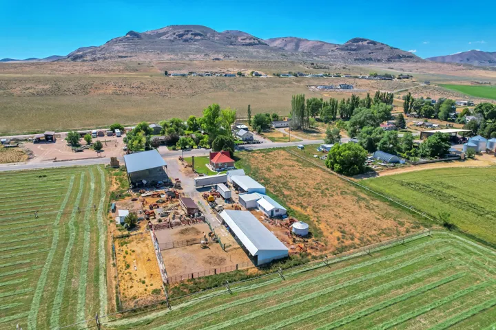 Expansive property featuring multiple outbuildings, agricultural fields, and a mountain backdrop