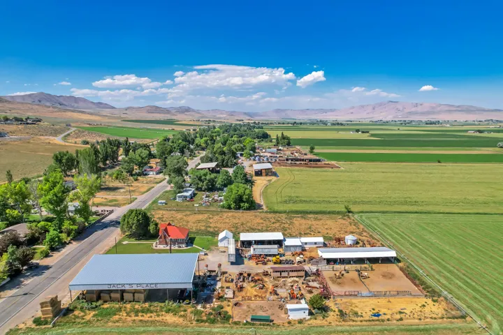 Expansive agricultural property featuring multiple outbuildings, open fields, and a large covered structure