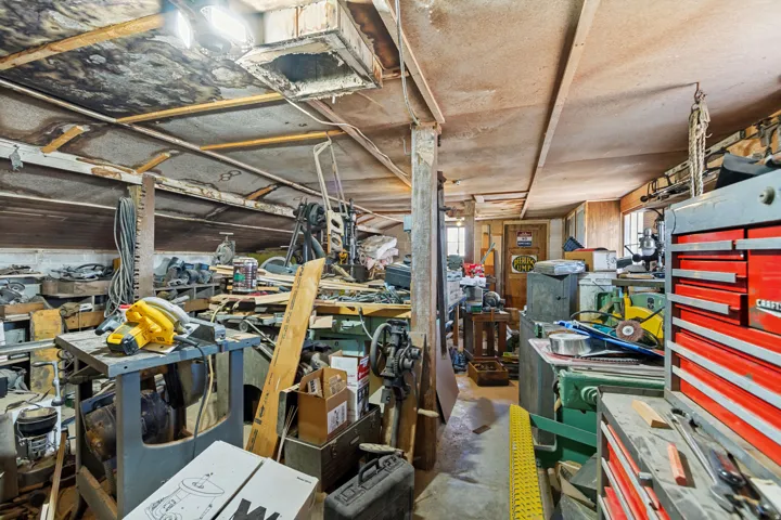 Workroom featuring exposed ceiling joists, strip lighting, and a window
