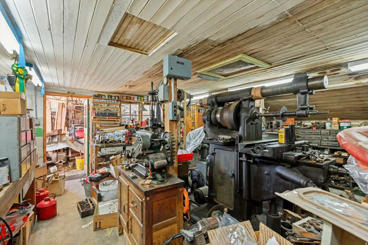 ' Spacious workshop featuring a . wood-finish plank ceiling, fluorescent lighting, and extensive built-in shelving