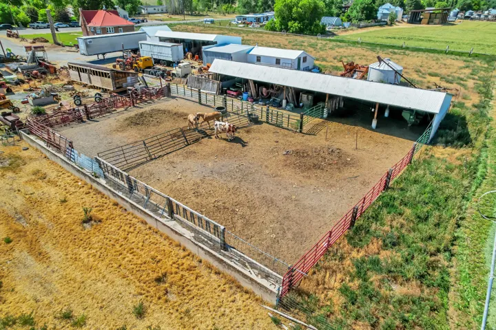 Spacious corral area with metal fencing, an open-sided shelter, and a metal grain silo