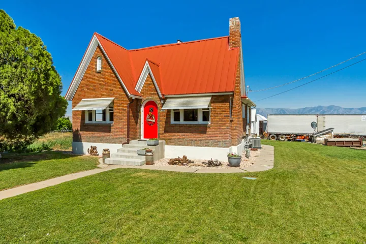 Brick exterior featuring a bright red metal roof and matching red entry door