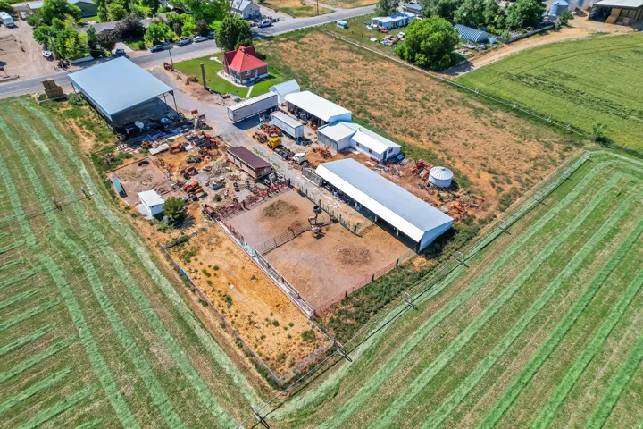 Expansive agricultural property featuring multiple outbuildings, fenced enclosures, and adjacent cultivated fields