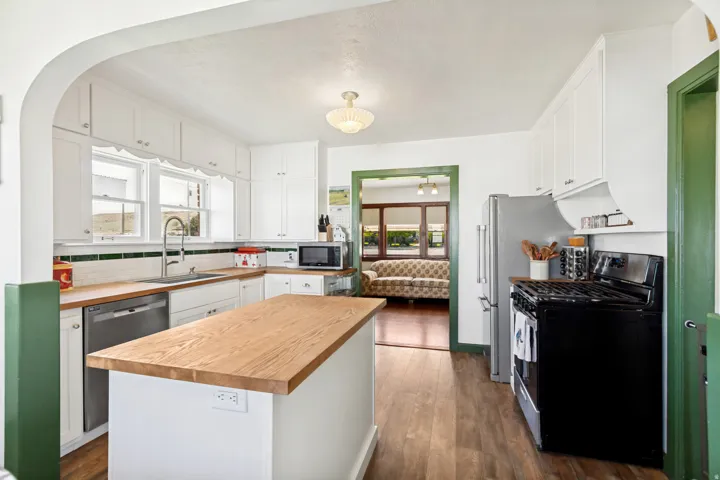Kitchen featuring white cabinetry, wood-finish countertops, stainless steel appliances, and wood-finish flooring