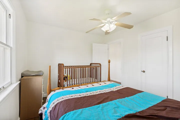 Bright room with a ceiling fan, white walls, and a window with white trim