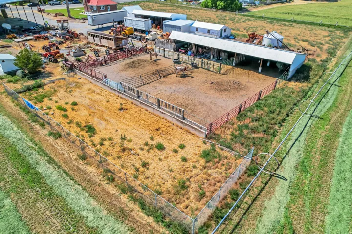 Expansive outdoor area featuring multiple fenced pens, a large covered structure, and additional storage buildings