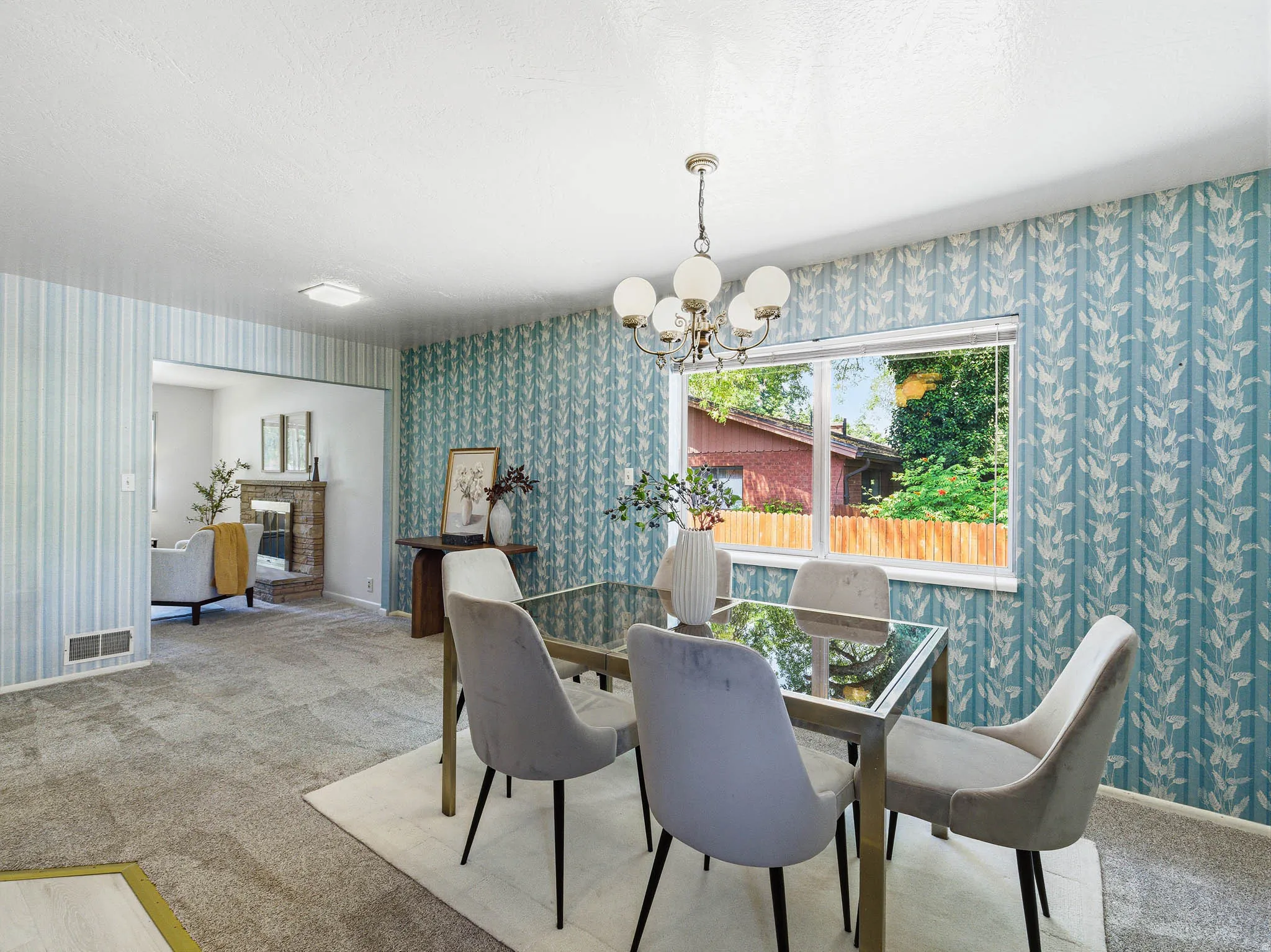 Dining area featuring patterned wallpaper, a window overlooking exterior greenery, and a chandelier with globe lights