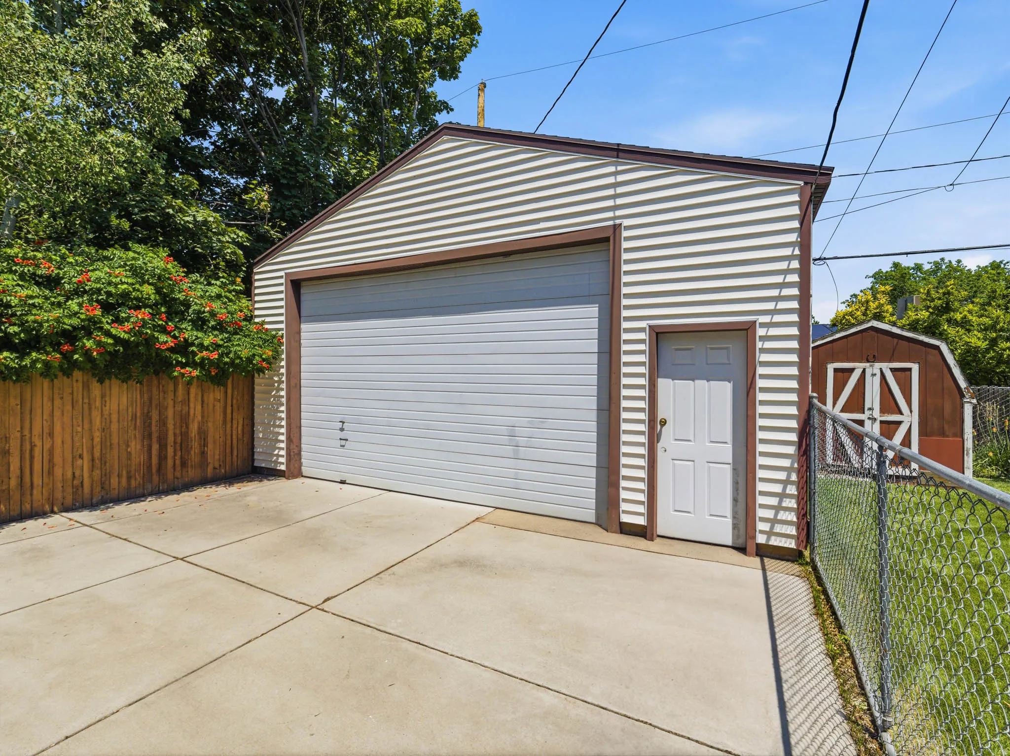 Detached garage with horizontal siding, a roll-up door, and a side entry door