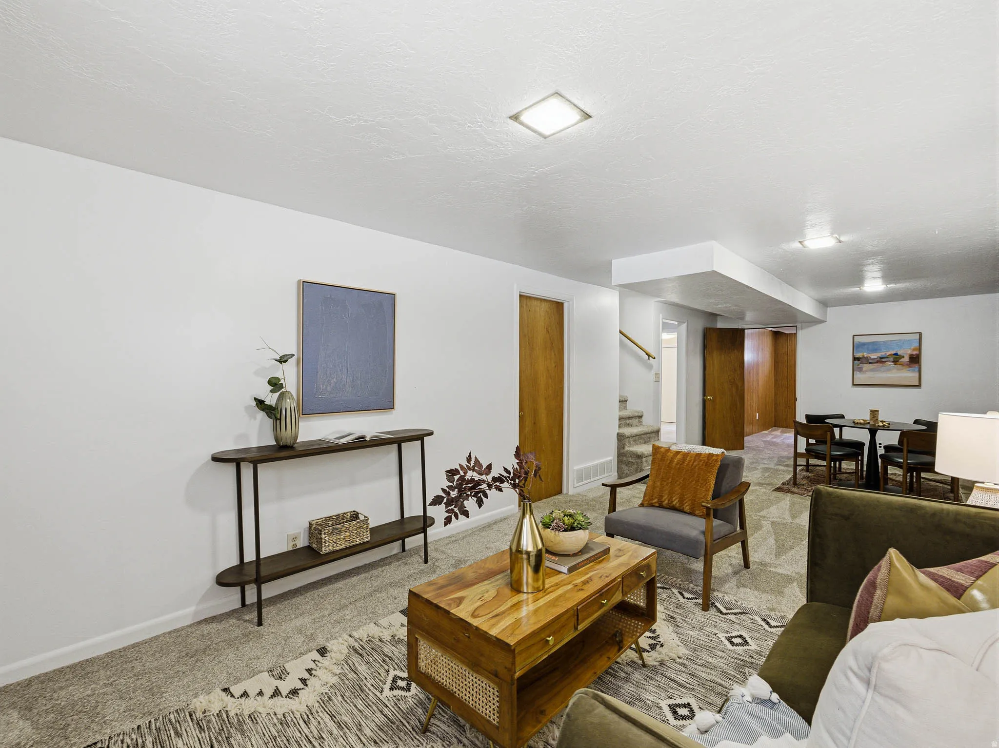 Spacious living area featuring neutral wall tones, recessed lighting, wood-finish doors, and a carpeted floor