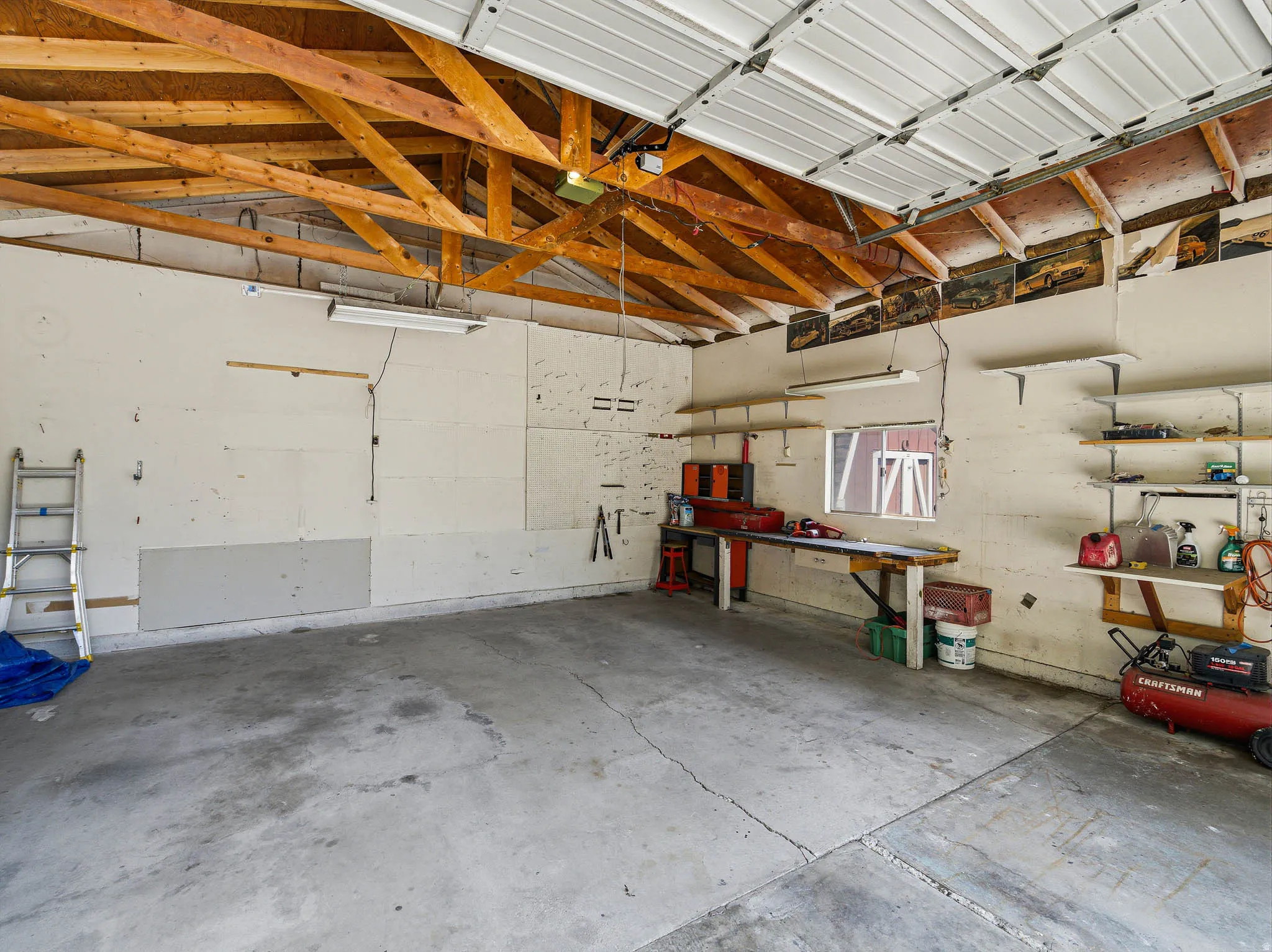 Attached garage interior featuring exposed wood ceiling trusses and a concrete floor