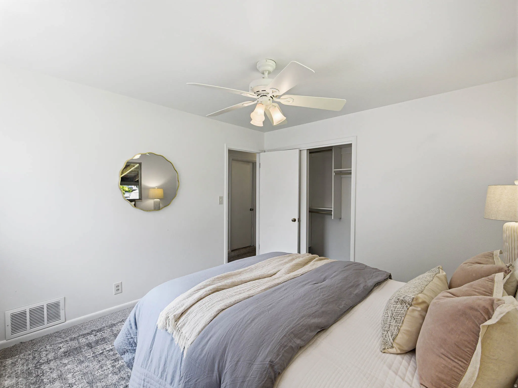 Bedroom featuring a ceiling fan with light fixture, white walls, and gray patterned carpeting
