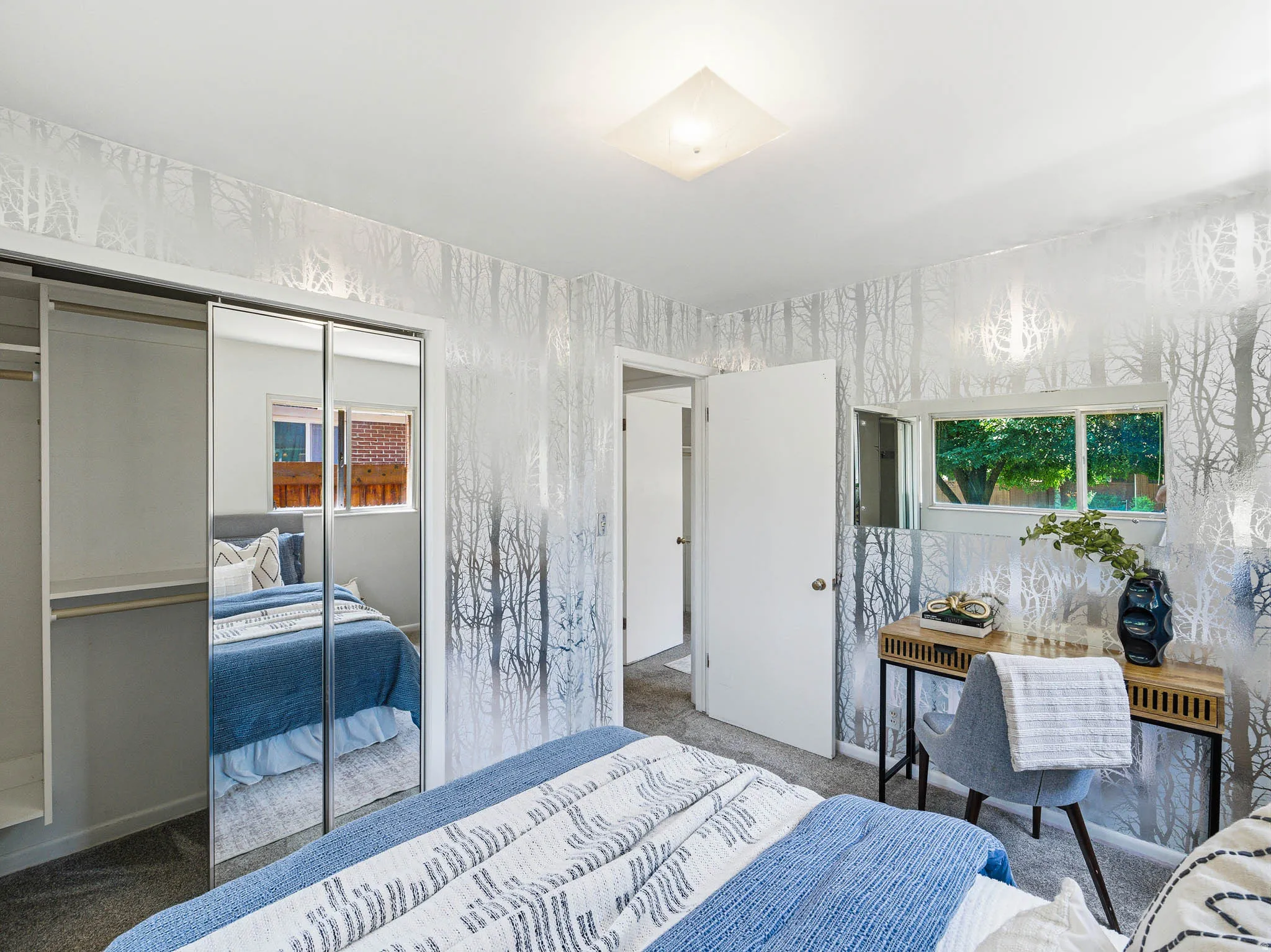 Bedroom featuring patterned wallpaper, mirrored closet doors, a double window, and a flush-mount ceiling light fixture