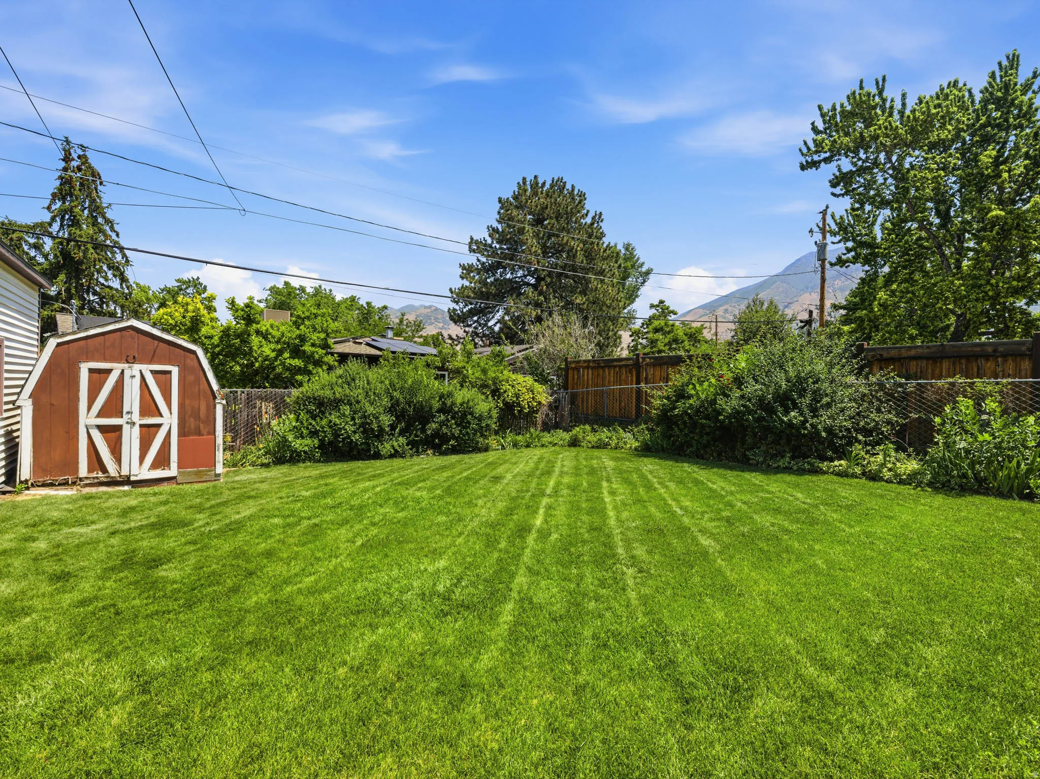 Expansive green lawn with a storage shed featuring white trim