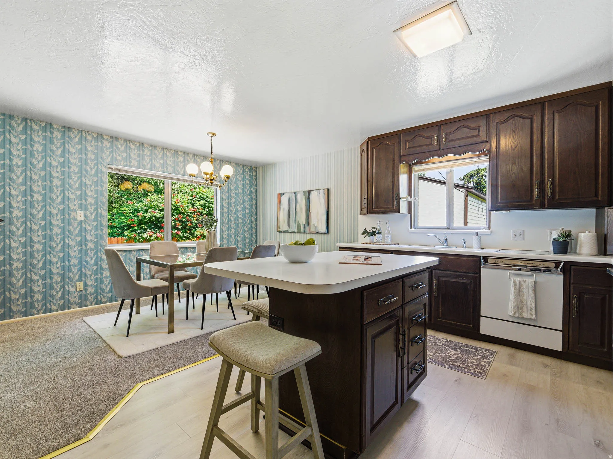 Open-concept kitchen and dining area featuring dark wood cabinetry, a central island with countertop seating, and light wood-finish flooring