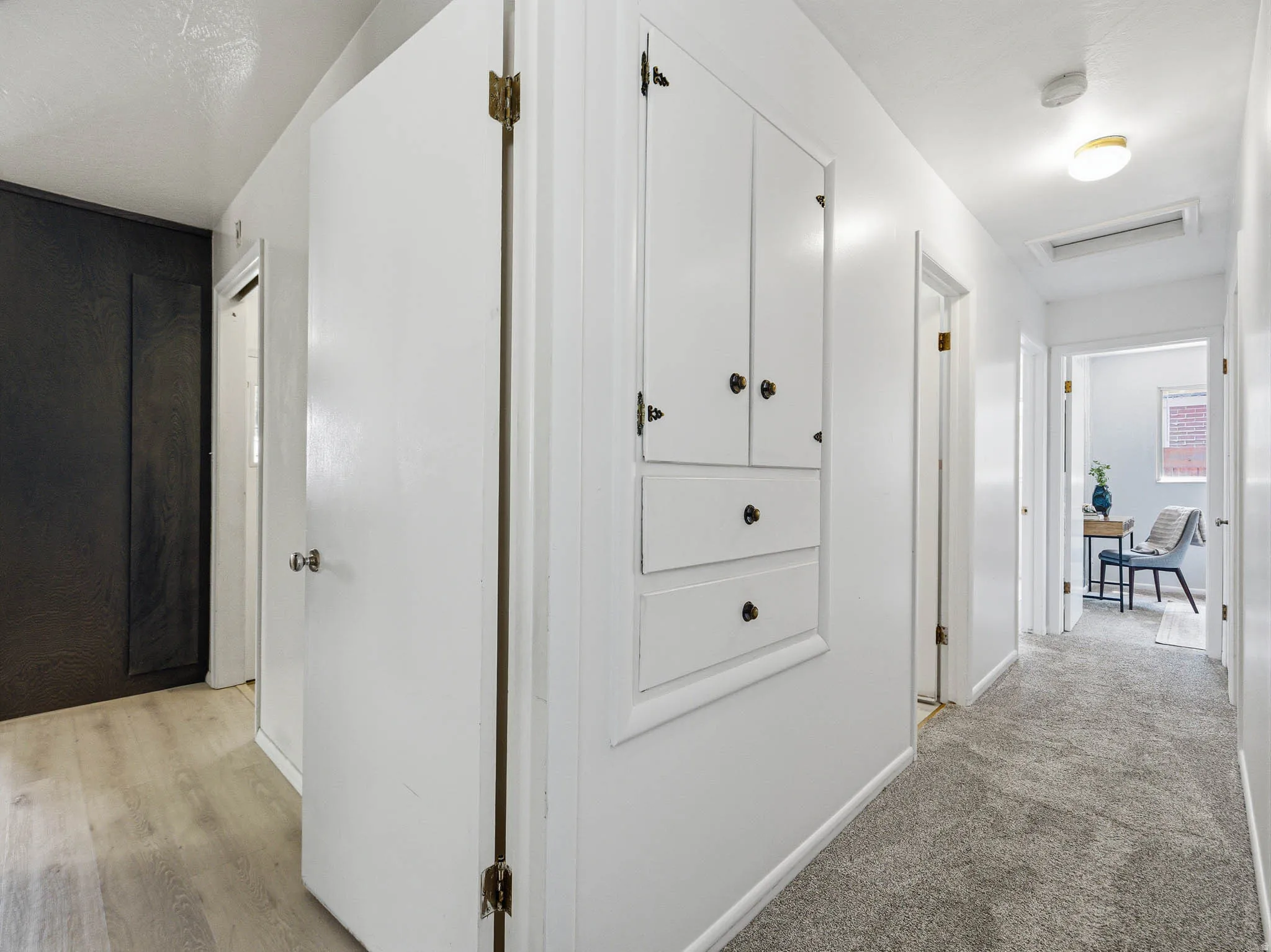 Hallway featuring white walls, a built-in storage cabinet with brass hardware, and recessed lighting