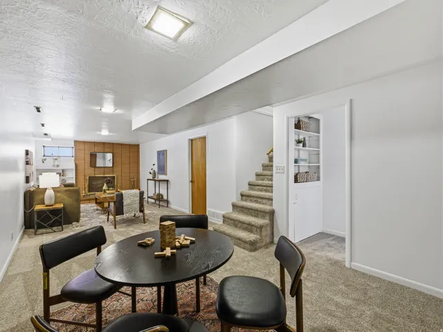 Carpeted recreation room featuring a wooden accent wall, built-in shelving, a fireplace with a brass firebox, and recessed lighting