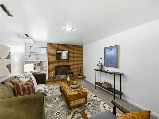 Living area featuring a brick fireplace with wood paneling, built-in shelving, carpet flooring, and recessed ceiling lighting