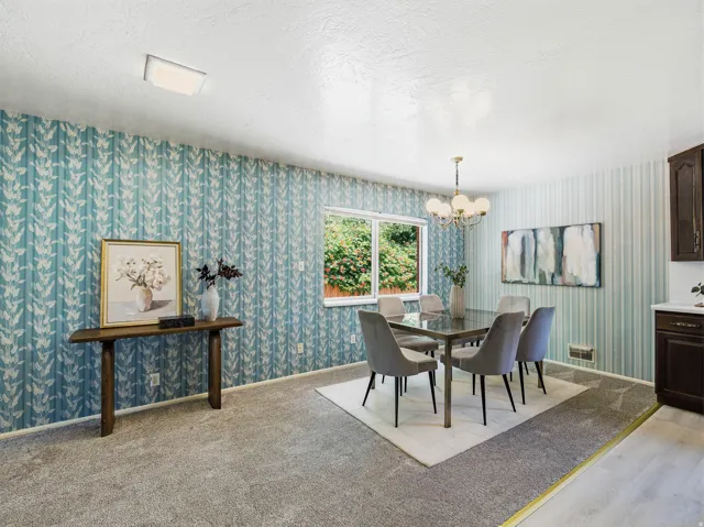 Dining space featuring patterned wallpaper, a central window, and a chandelier-style light fixture