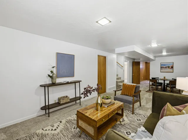 Spacious living area featuring neutral wall tones, recessed lighting, wood-finish doors, and a carpeted floor