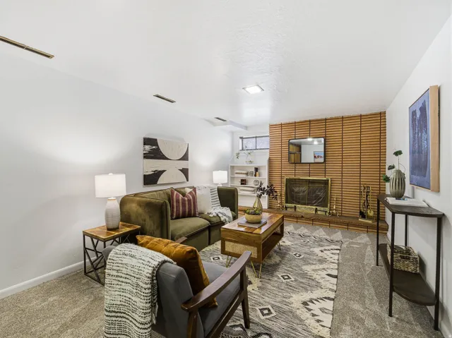 Living area featuring a brick fireplace with a wood-slat surround, carpet flooring, recessed lighting, and built-in shelving