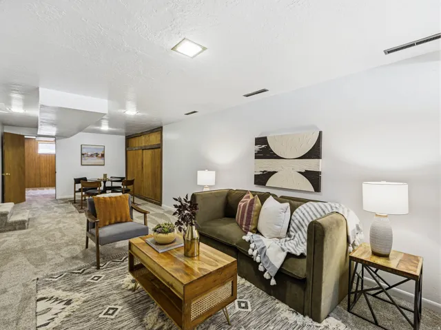 Carpeted living area featuring recessed lighting, white walls, and a built-in wooden storage unit with sliding doors