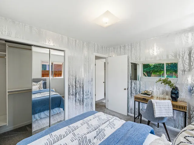 Bedroom featuring patterned wallpaper, mirrored closet doors, a double window, and a flush-mount ceiling light fixture
