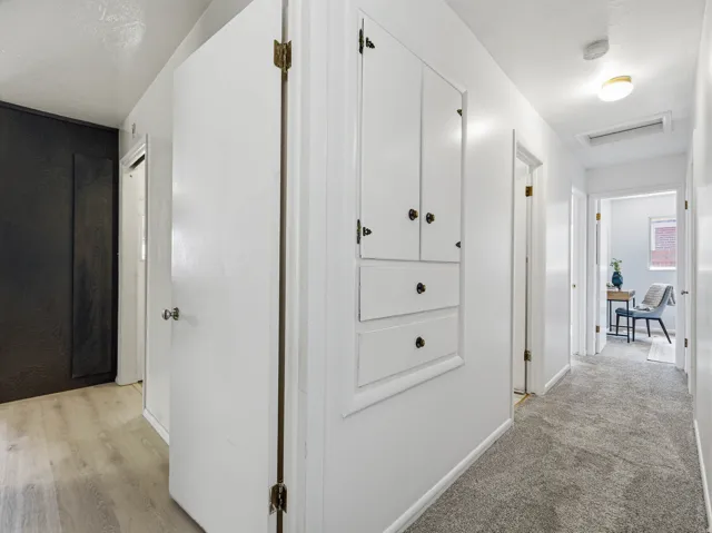 Hallway featuring white walls, a built-in storage cabinet with brass hardware, and recessed lighting