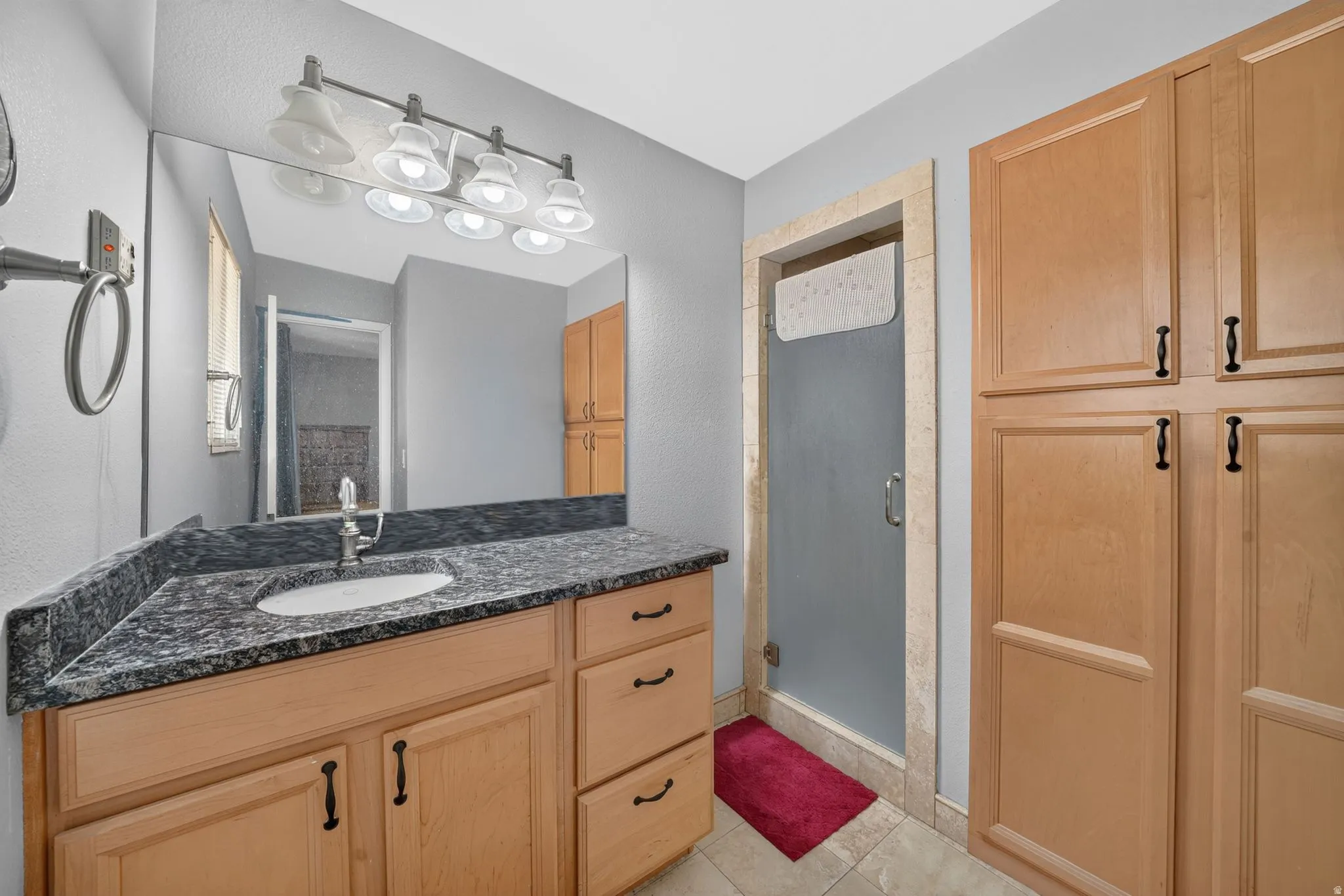 ON SUITE bathroom MASTER:Bathroom vanity featuring a granite-style countertop with an integrated sink, natural wood-finish cabinetry, and a framed shower with a frosted glass door