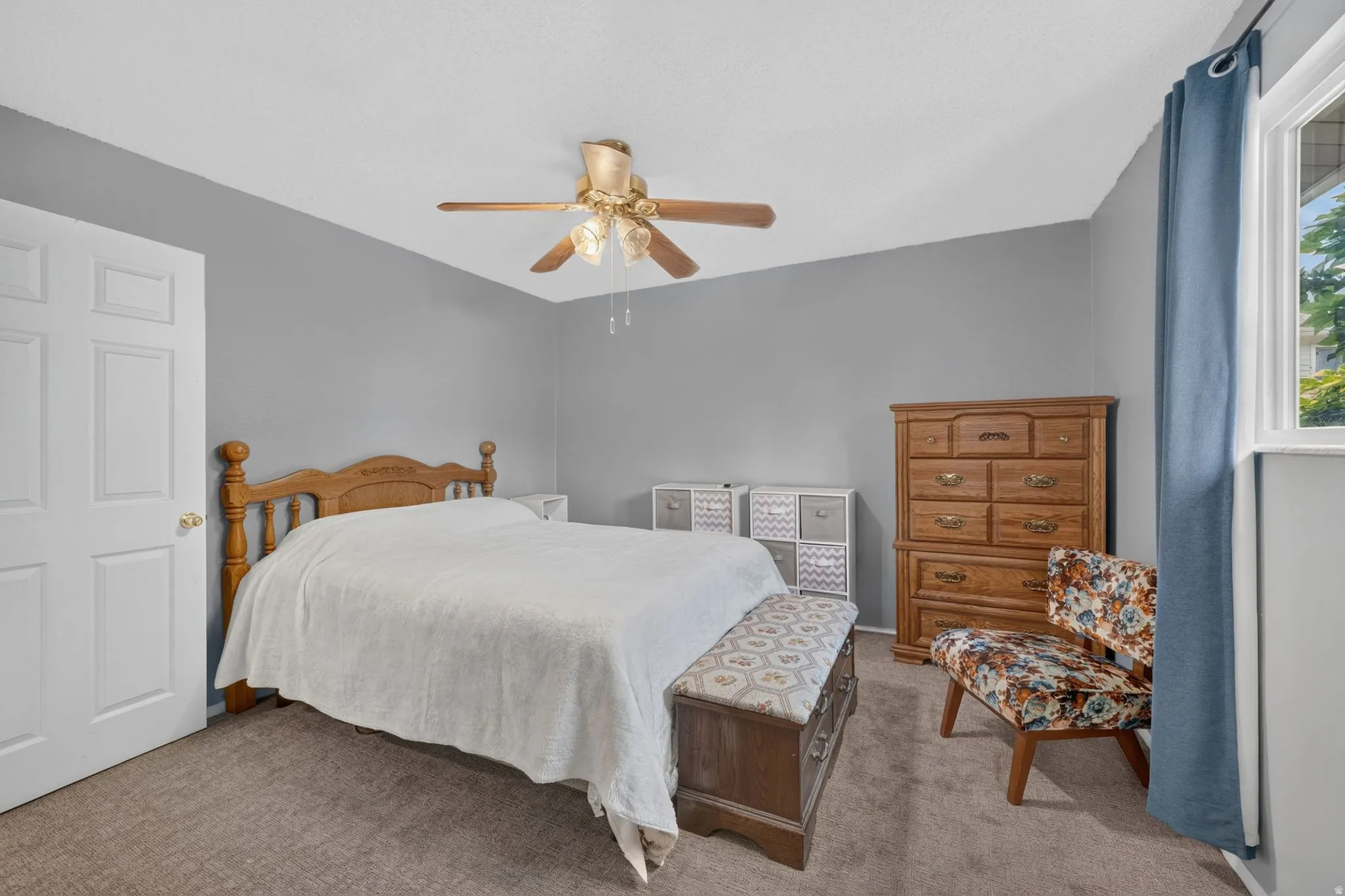 Carpeted MASTER bedroom featuring a ceiling fan with integrated lighting, a white paneled door, and a window with blue curtains