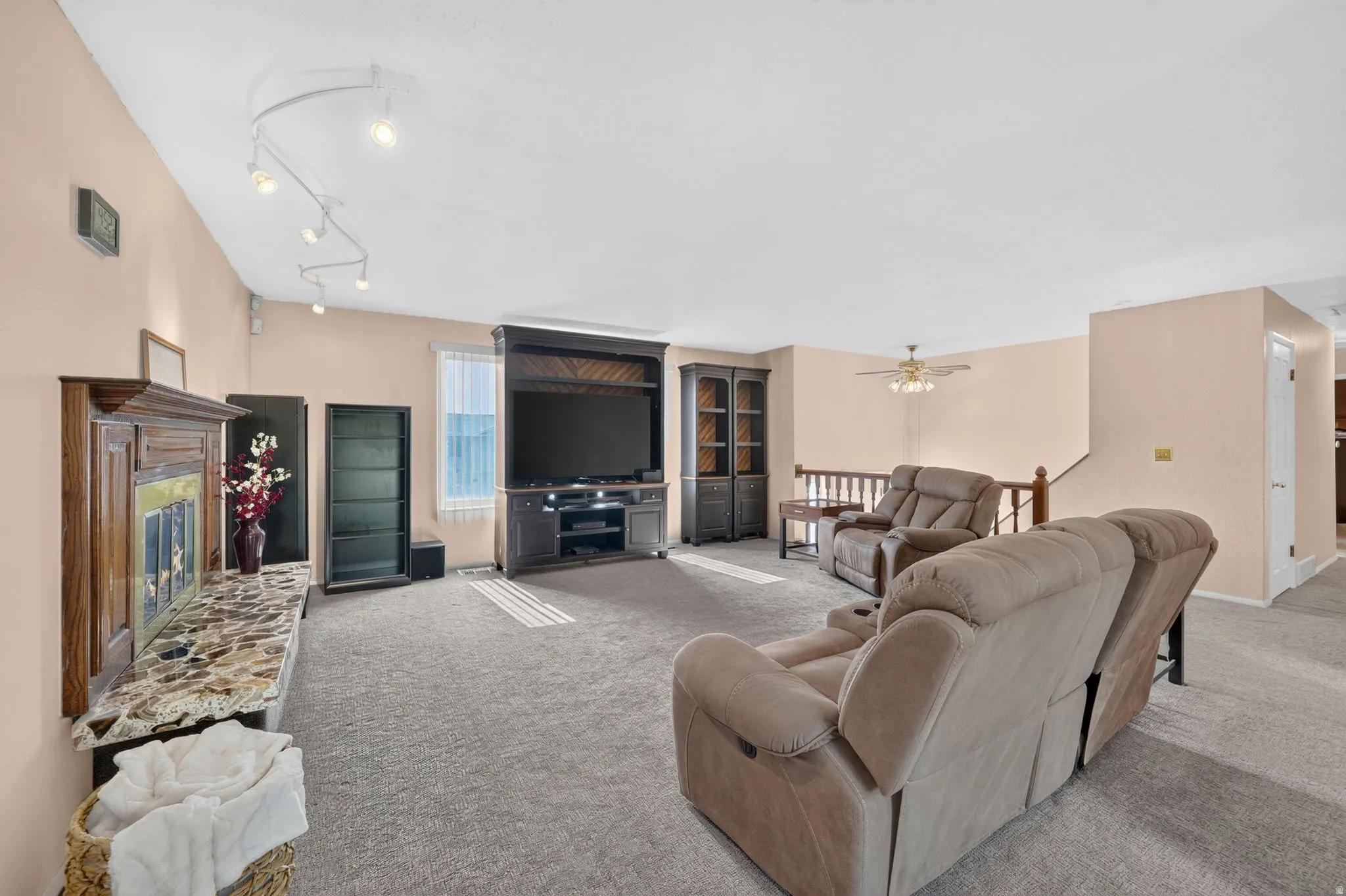 Carpeted living area featuring a fireplace with a decorative mantel and stone-finish hearth