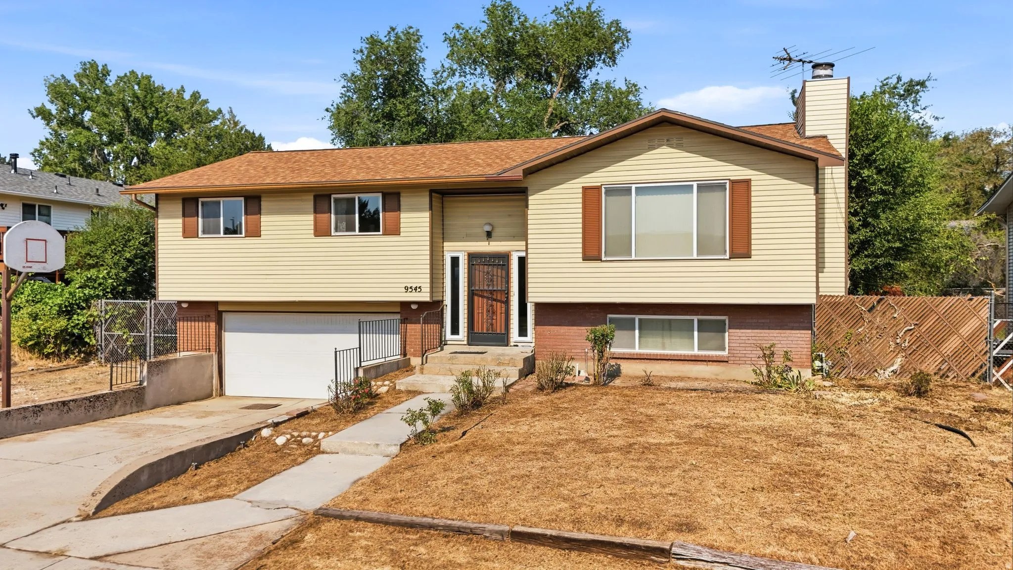 Split-level residence featuring light beige siding and a warm brown roof