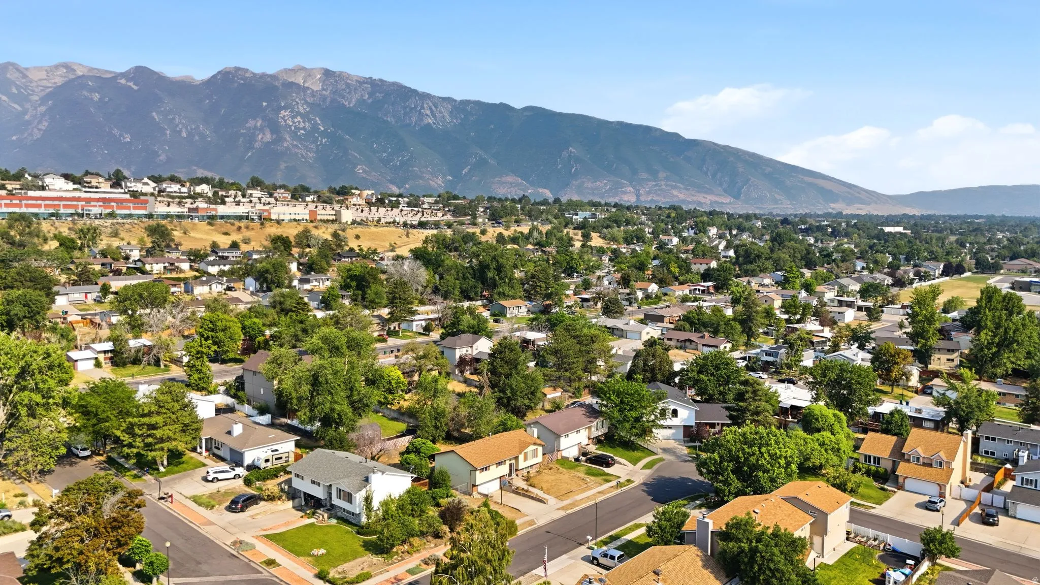Residential neighborhood featuring mature trees and mountain scenery