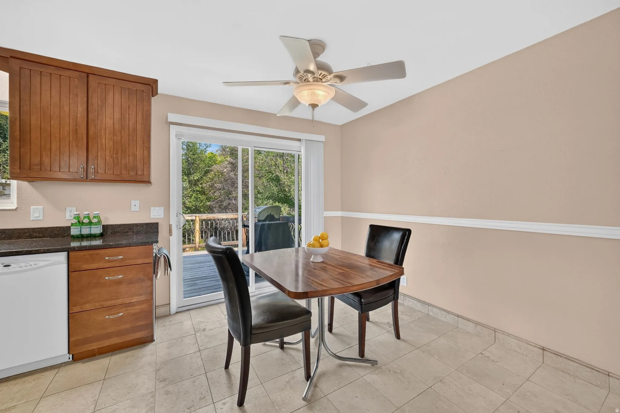 Kitchen area featuring wood cabinetry, dark granite-style countertops, and a white dishwasher
