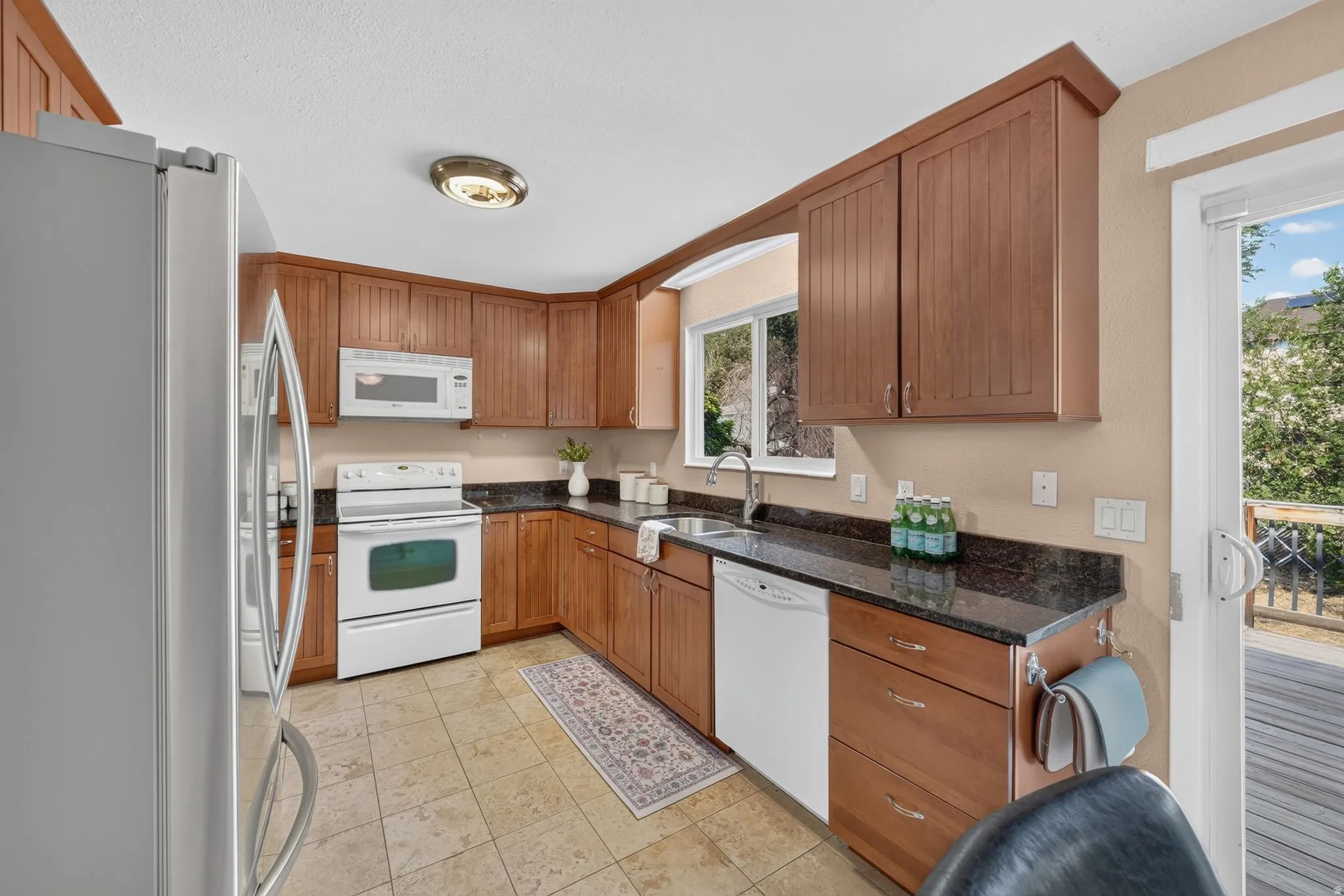 Kitchen featuring wood cabinetry, dark countertops, a built-in microwave, and a window above the sink