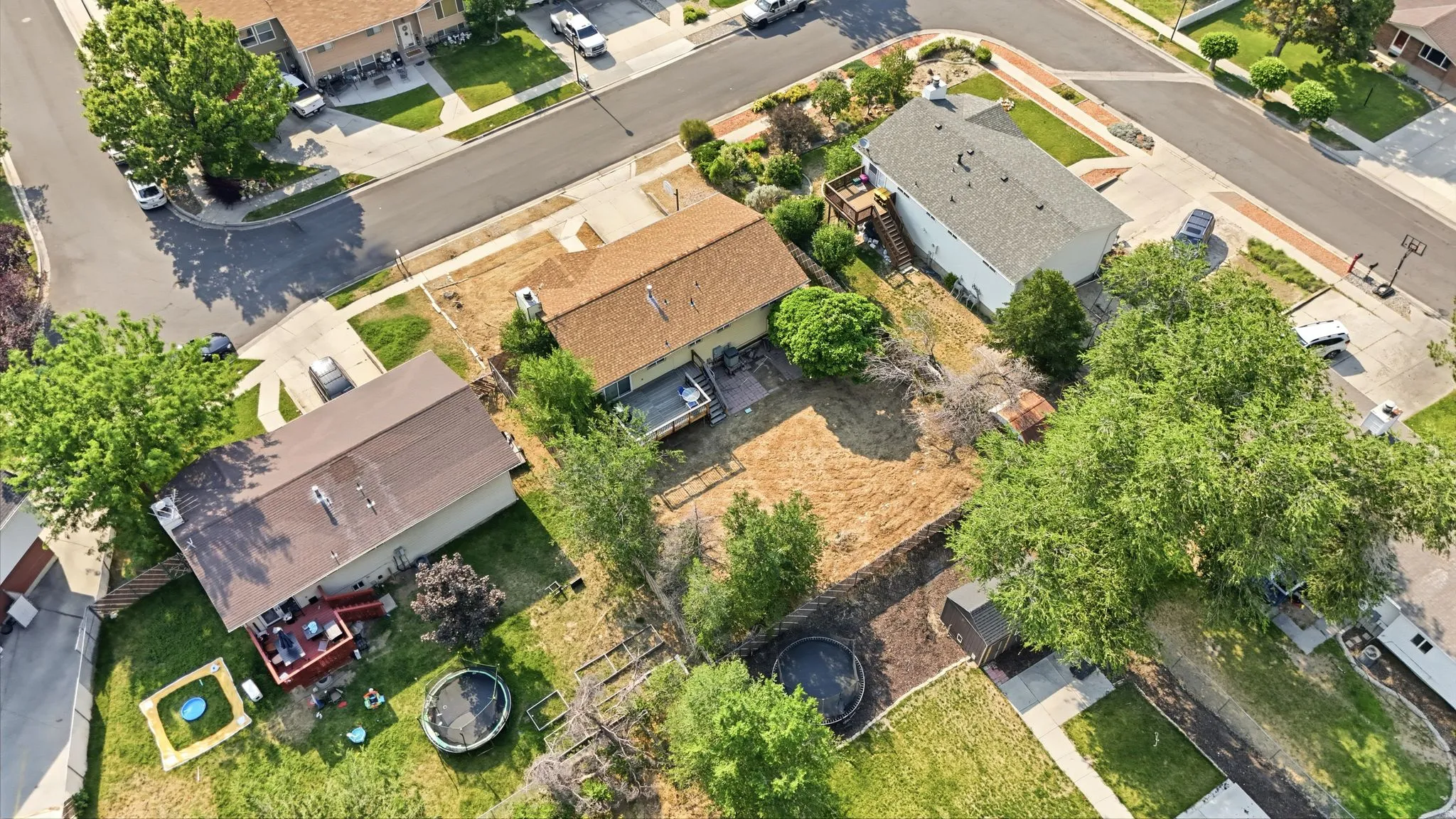 Corner lot property featuring a light brown roof and a paved driveway
