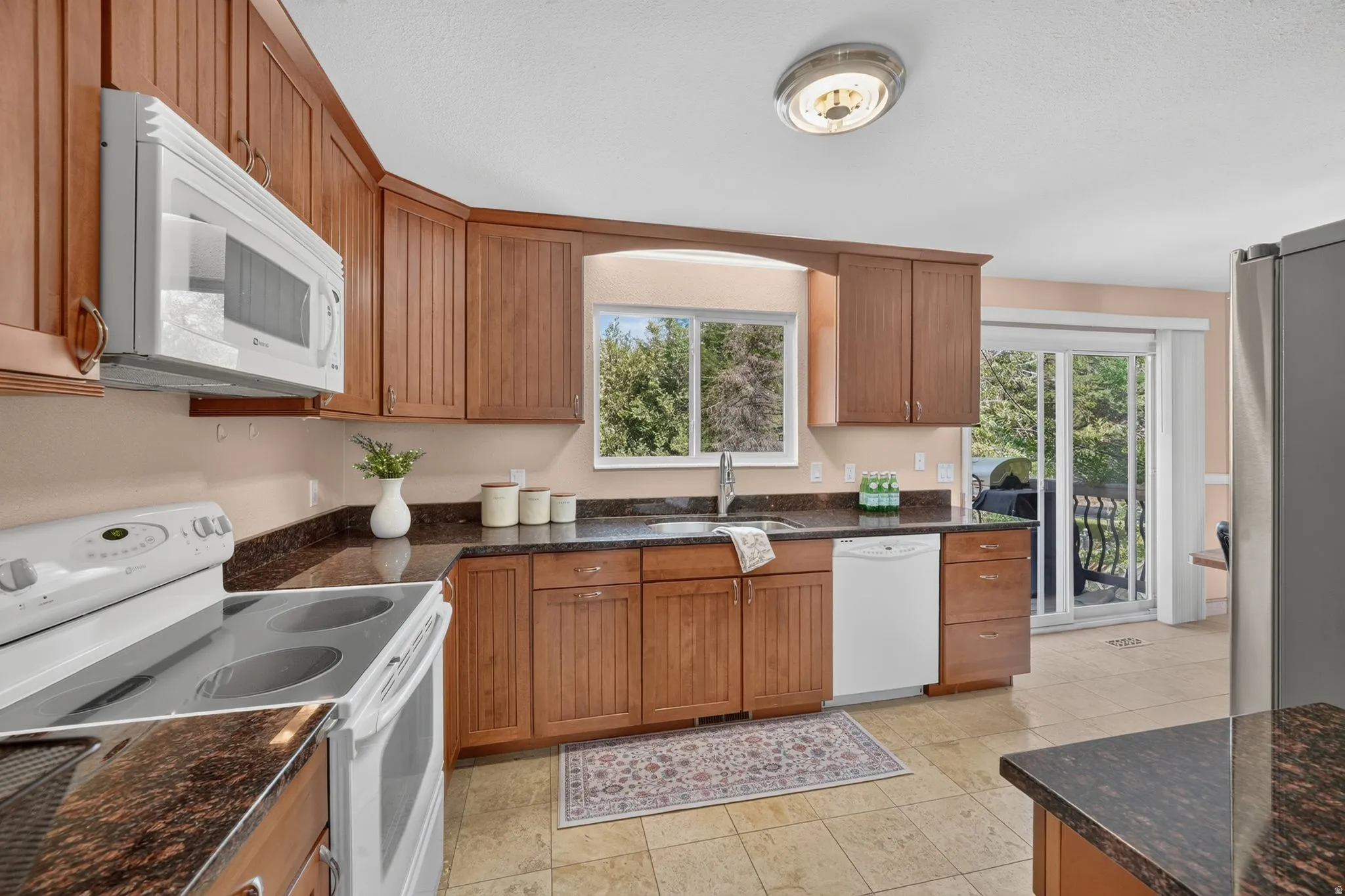 Kitchen featuring wood cabinetry, dark speckled countertops, and an undermount sink