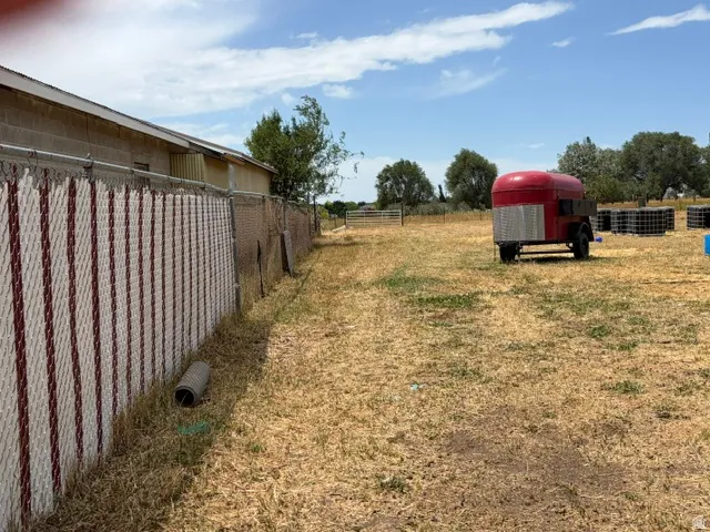 Expansive parcel featuring a chain-link fence with privacy slats, open field space, and distant mature trees