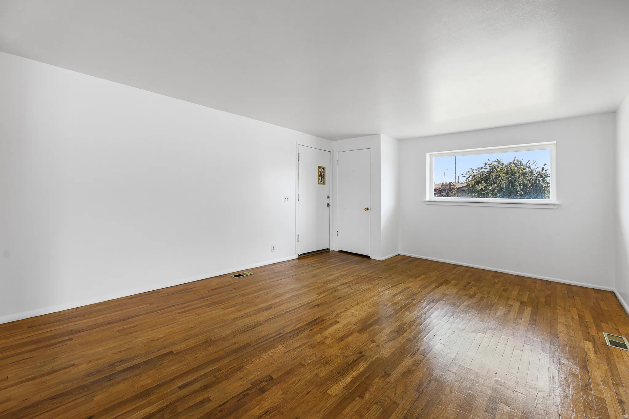 Another angle of living room featuring original flooring - recently stained. New paint.