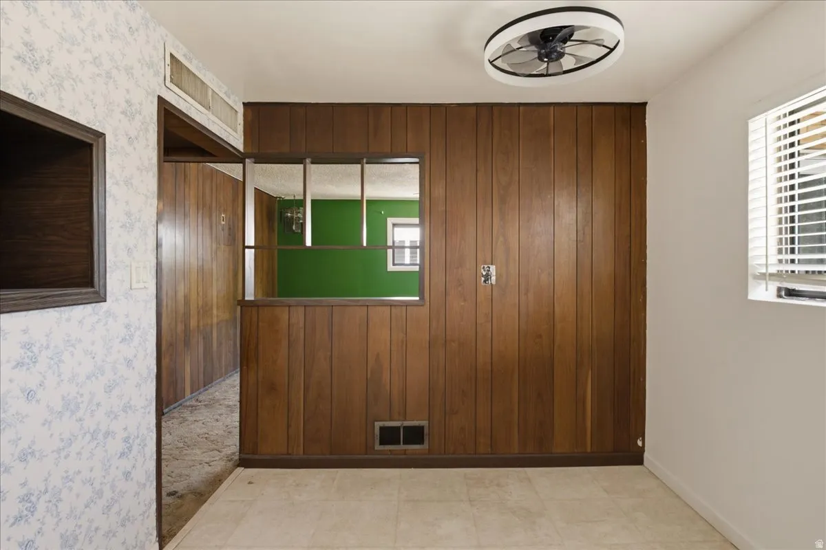 Interior space featuring wood paneling, wall-mounted shelving unit, and a ceiling fan