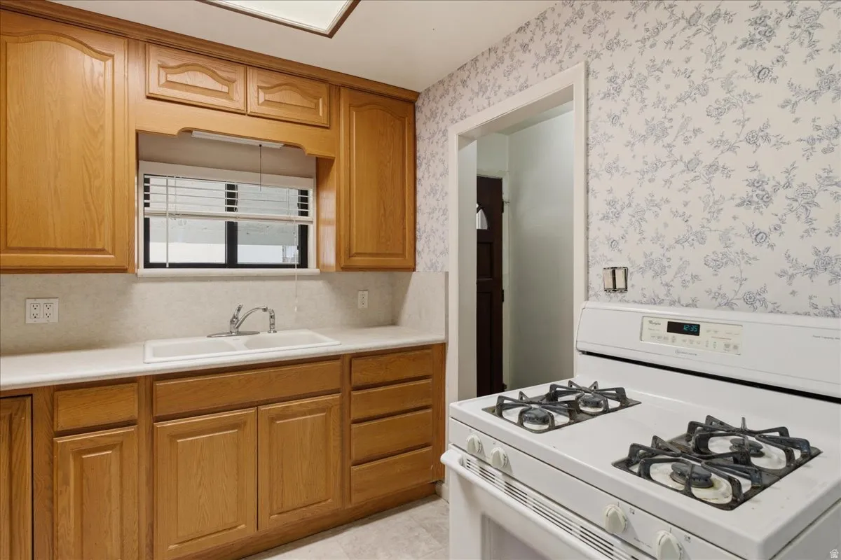 Kitchen featuring wood cabinetry, solid surface countertops, white tile backsplash, and a double basin sink with a chrome faucet