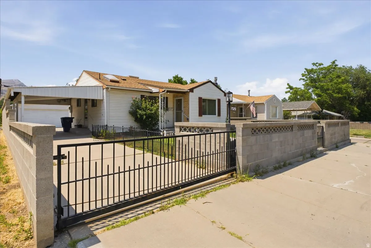 Secured property entrance featuring a black metal sliding gate, concrete block perimeter wall, and a concrete driveway