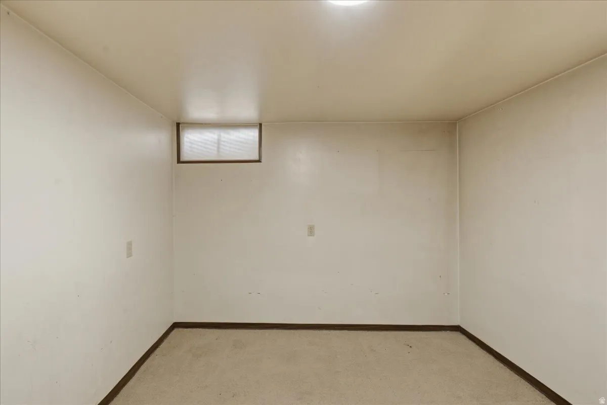 Carpeted room with a high-set window, baseboard trim, and overhead lighting