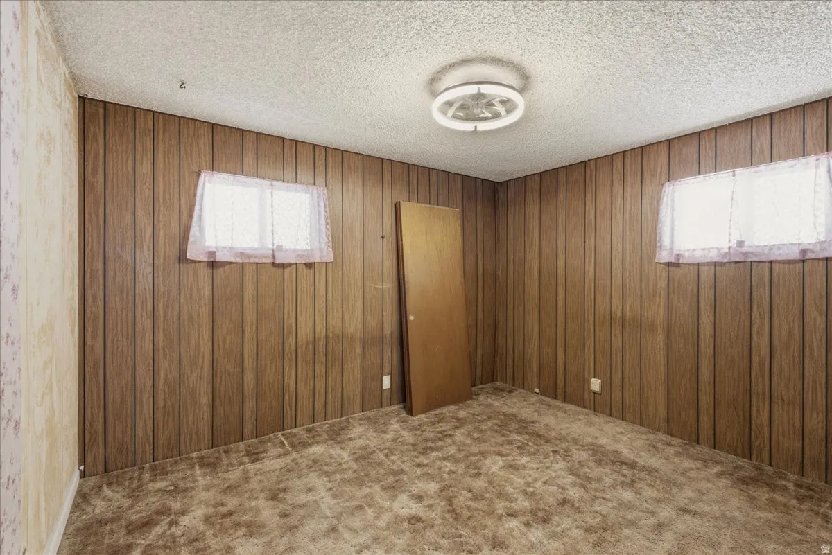 Room featuring wood paneling on multiple walls and textured ceiling