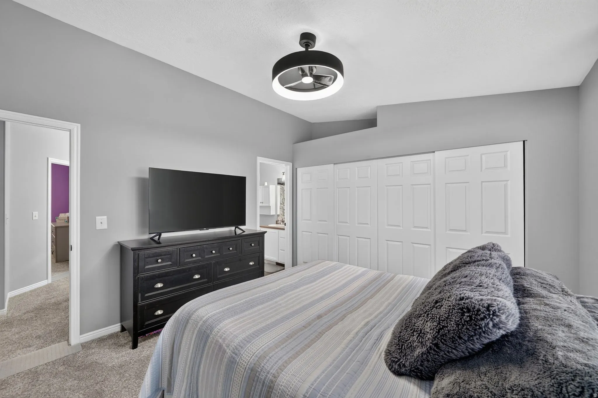 Bedroom featuring light gray walls, carpet flooring, a ceiling-mounted light fixture, and white bi-fold closet doors