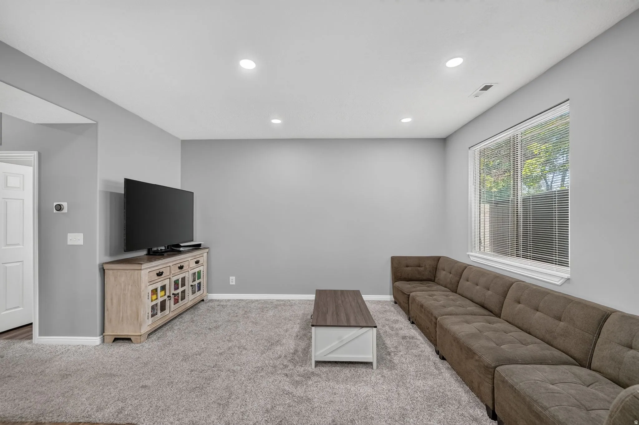 Carpeted living space with recessed lighting and a large window