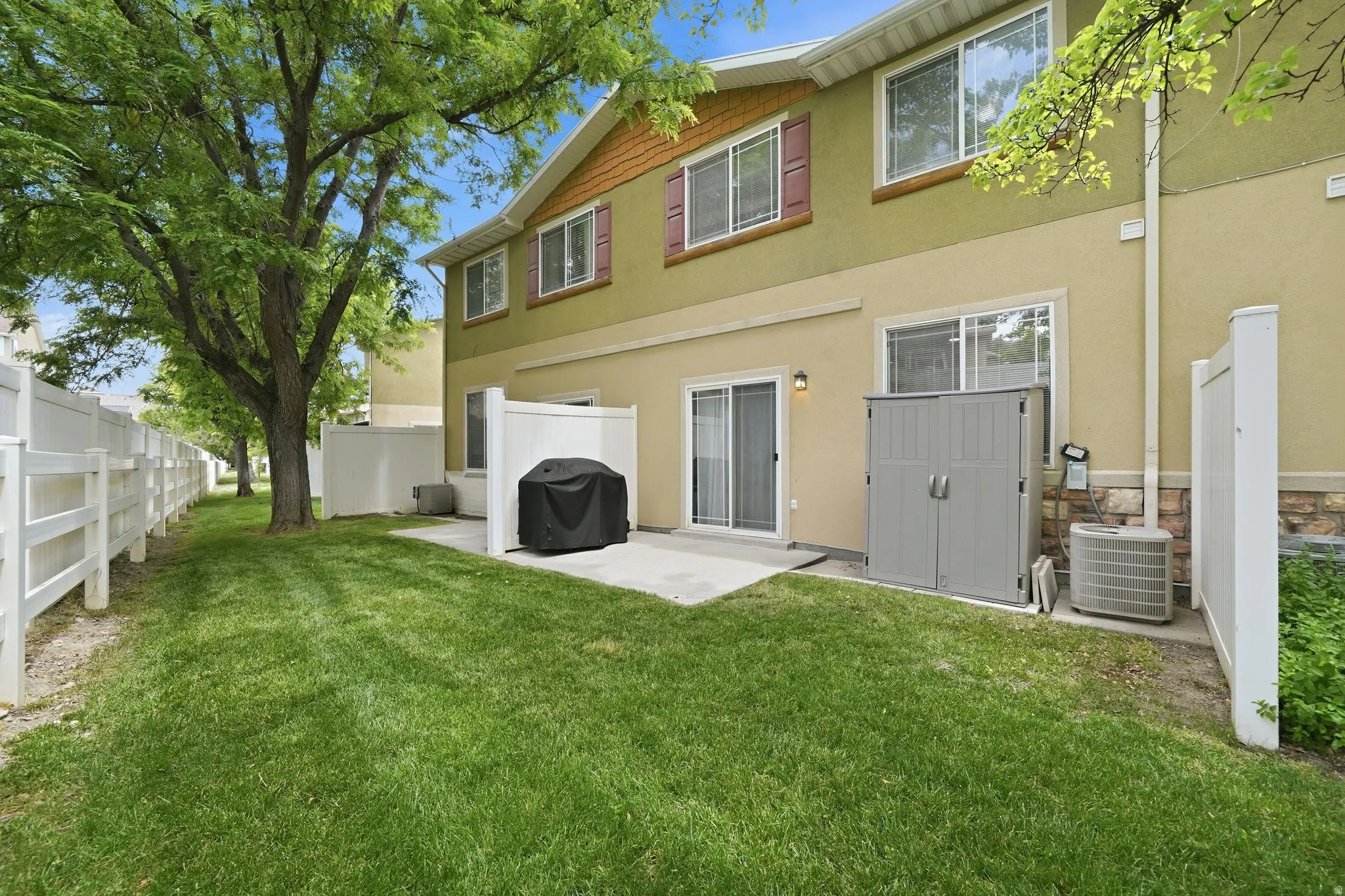 Expansive green space featuring mature trees and a white picket fence