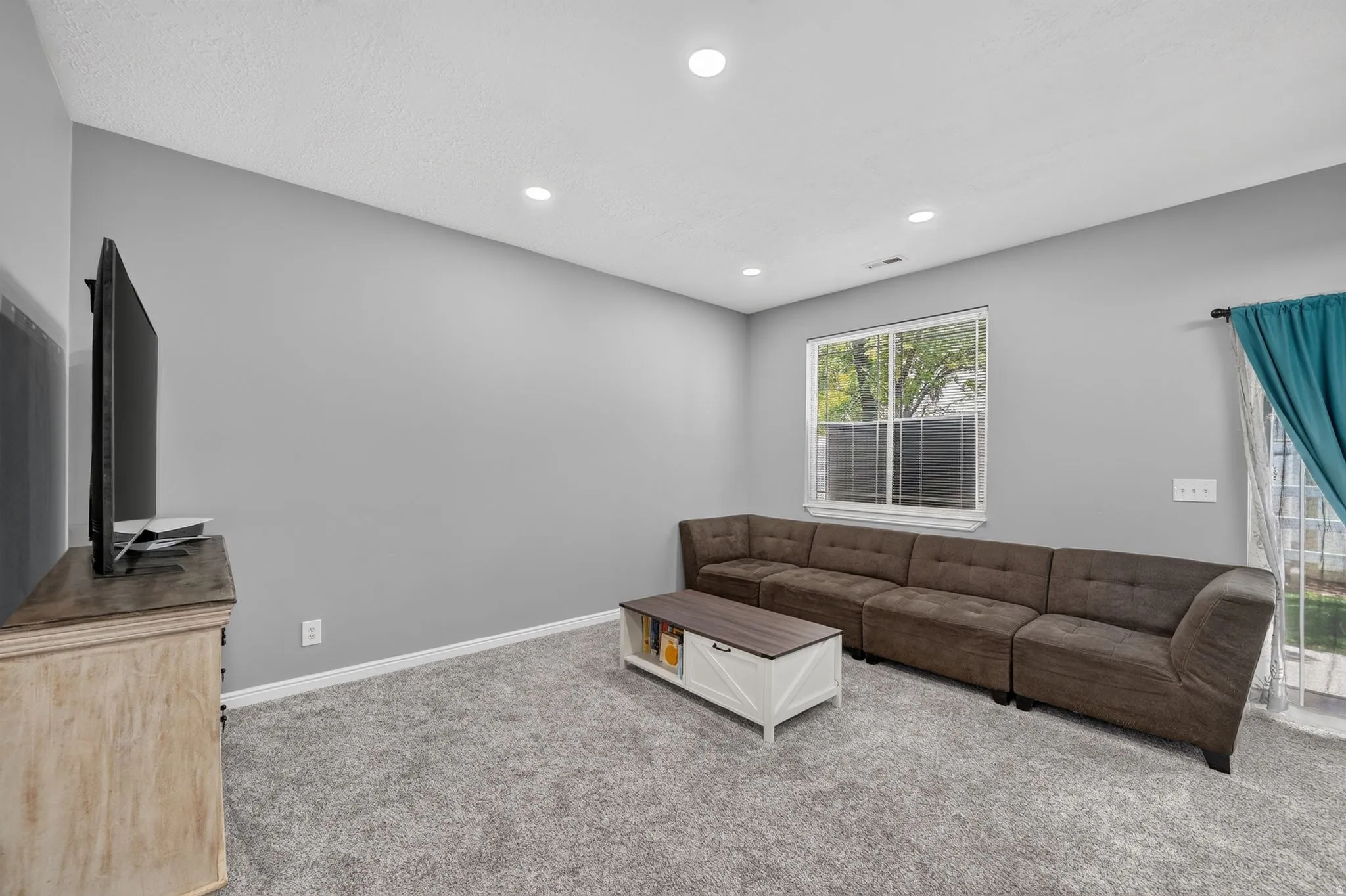 Spacious room featuring neutral grey walls and recessed lighting