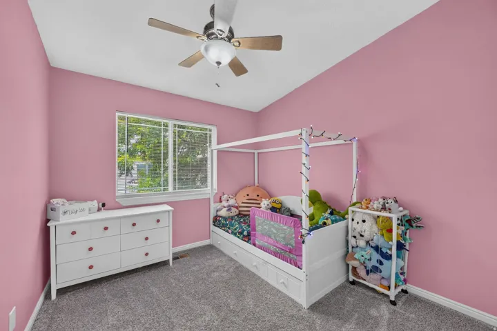 Room featuring a window with exterior views, a ceiling fan with integrated lighting, and neutral-toned carpeting