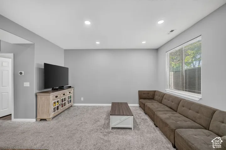 Carpeted living space with recessed lighting and a large window